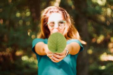 young girl holding big green leaf